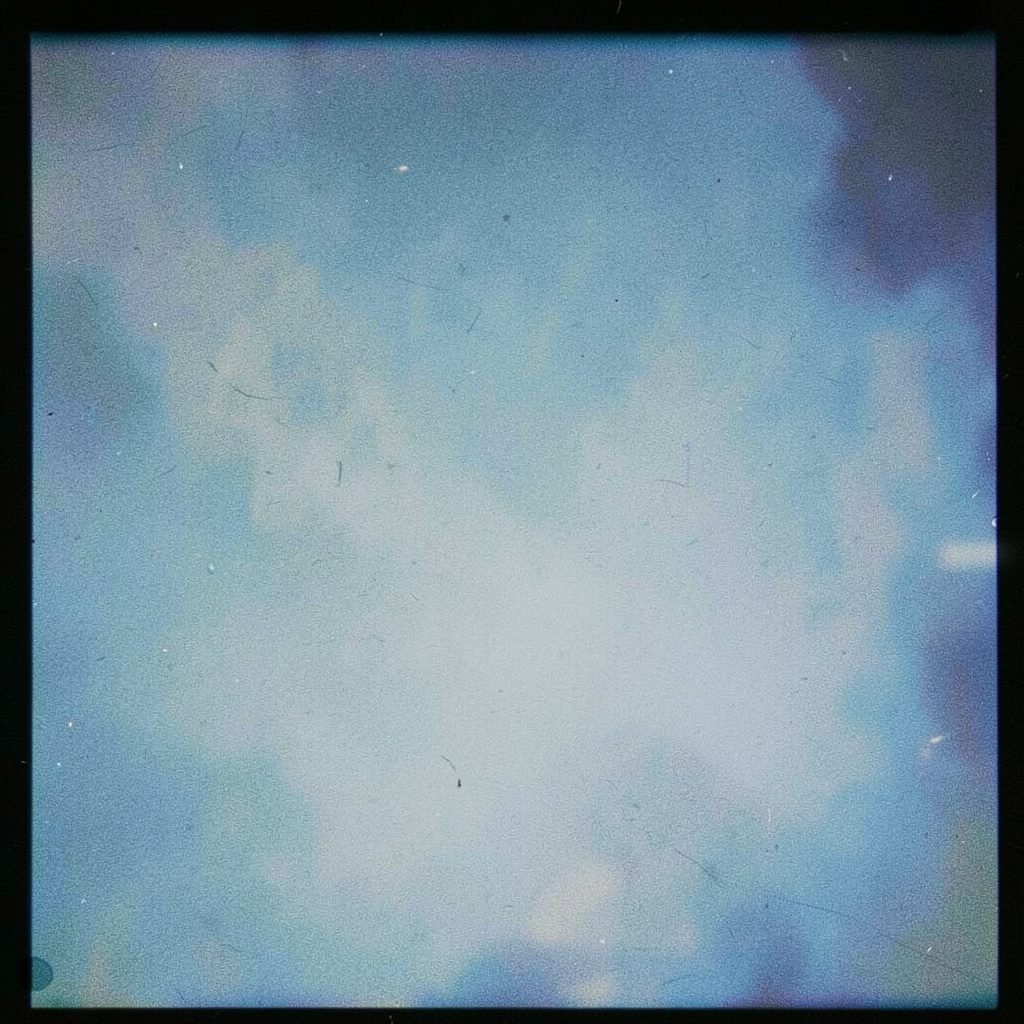 A film photograph with visible grain in gentle rose and sky-blue tones, abstract and serene.